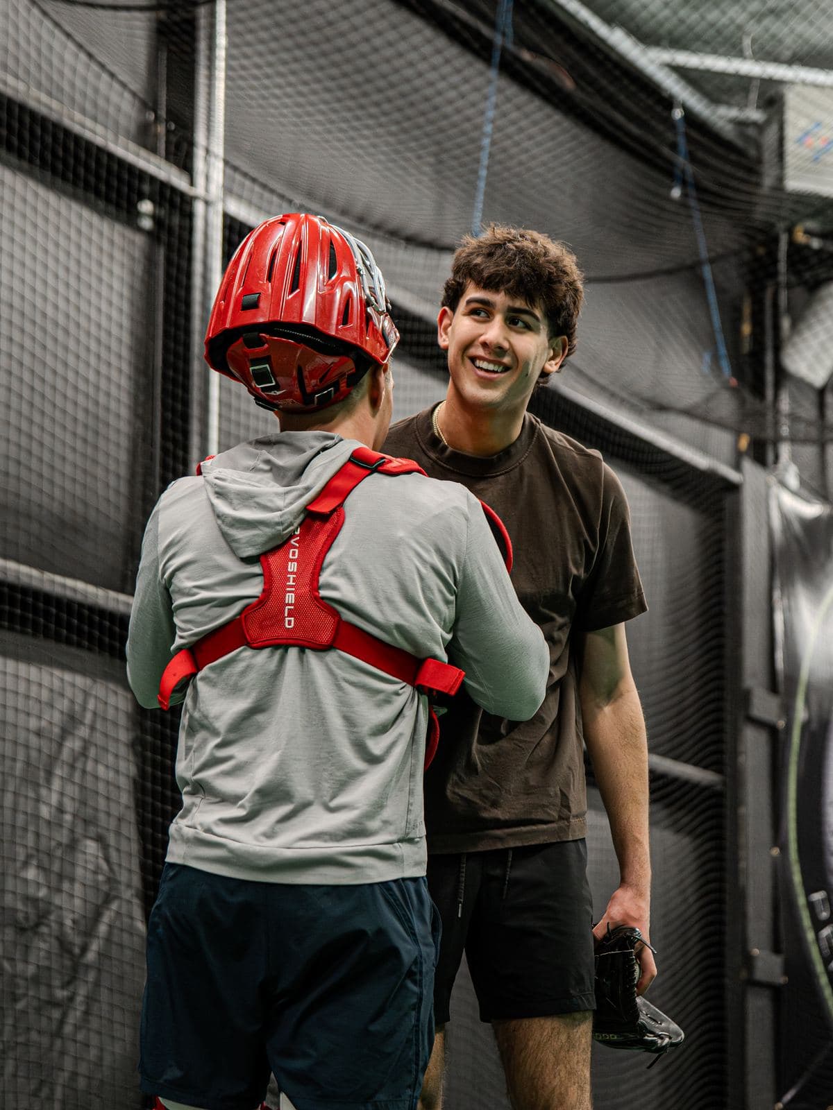 A PPL coach smiling and talking with an athlete in catcher gear between reps