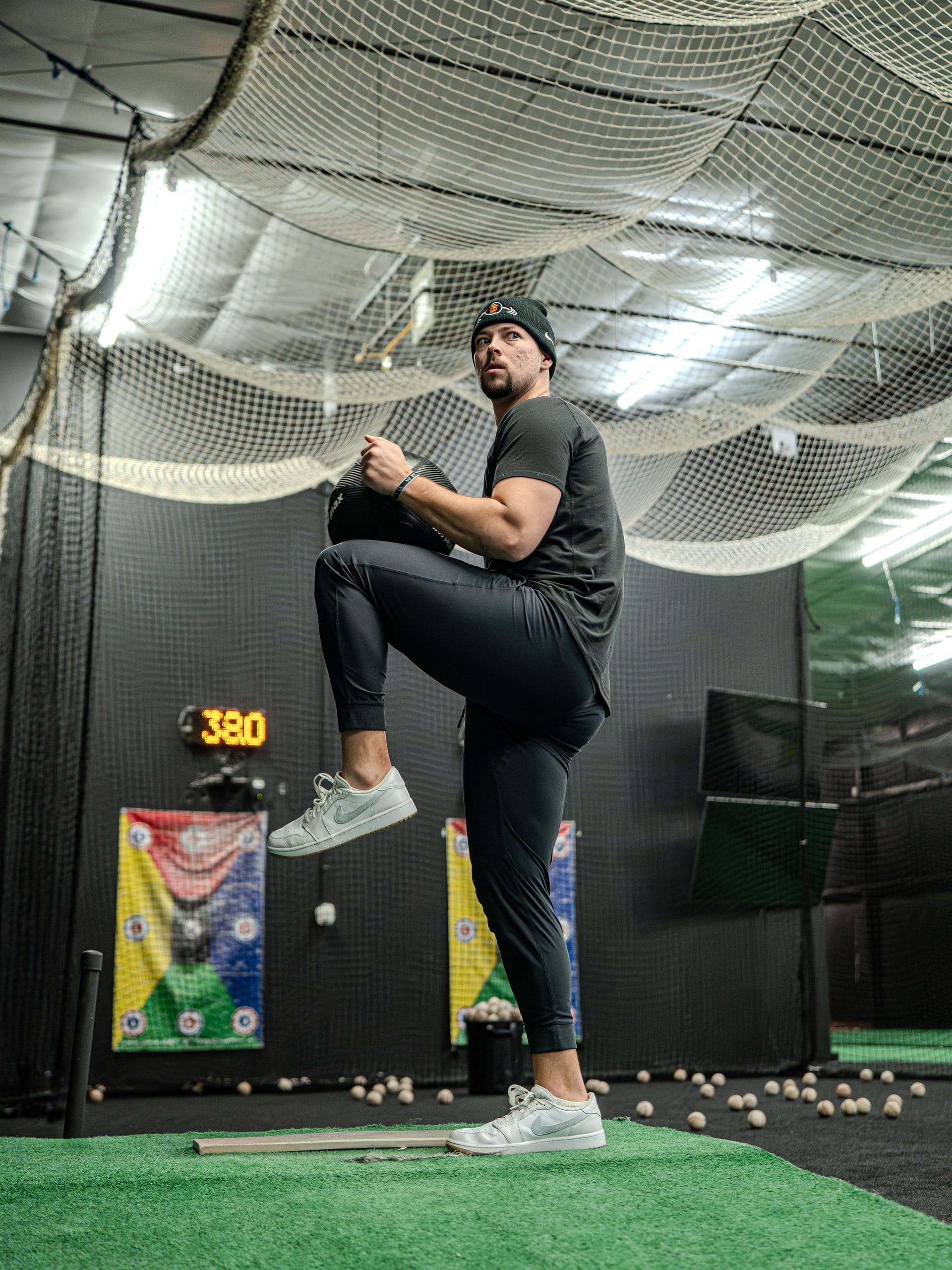 A pitcher at the top of his leg lift in a PPL tunnel with the velocity readout behind him