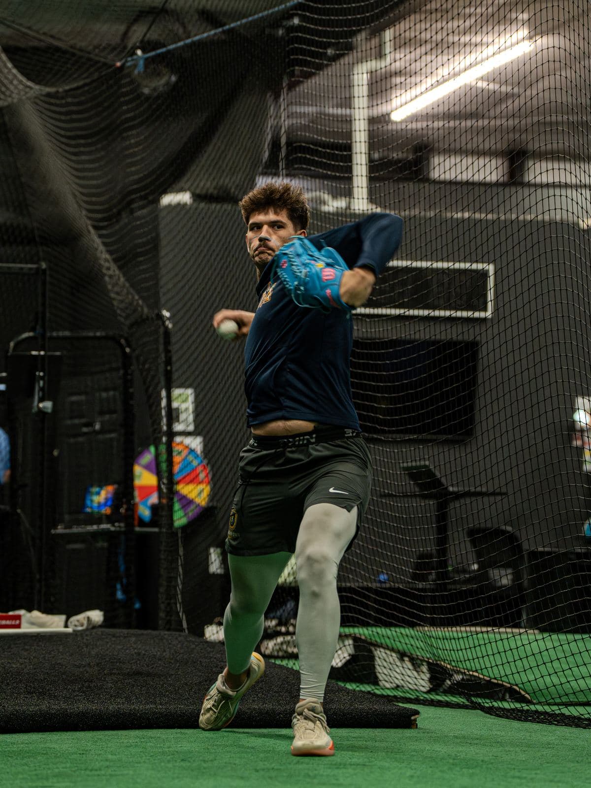 A pitcher striding toward the net during a throwing session at PPL