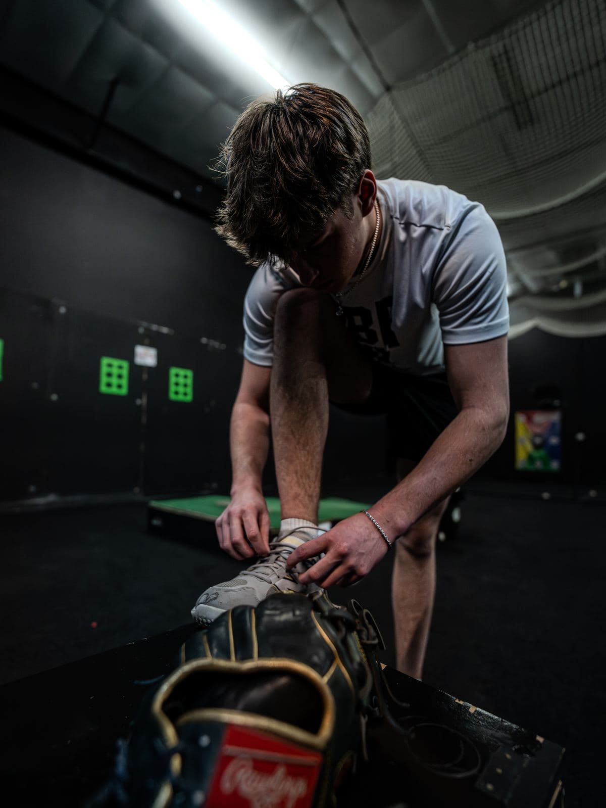 A PPL athlete lacing up before a session, his glove on the bench beside him