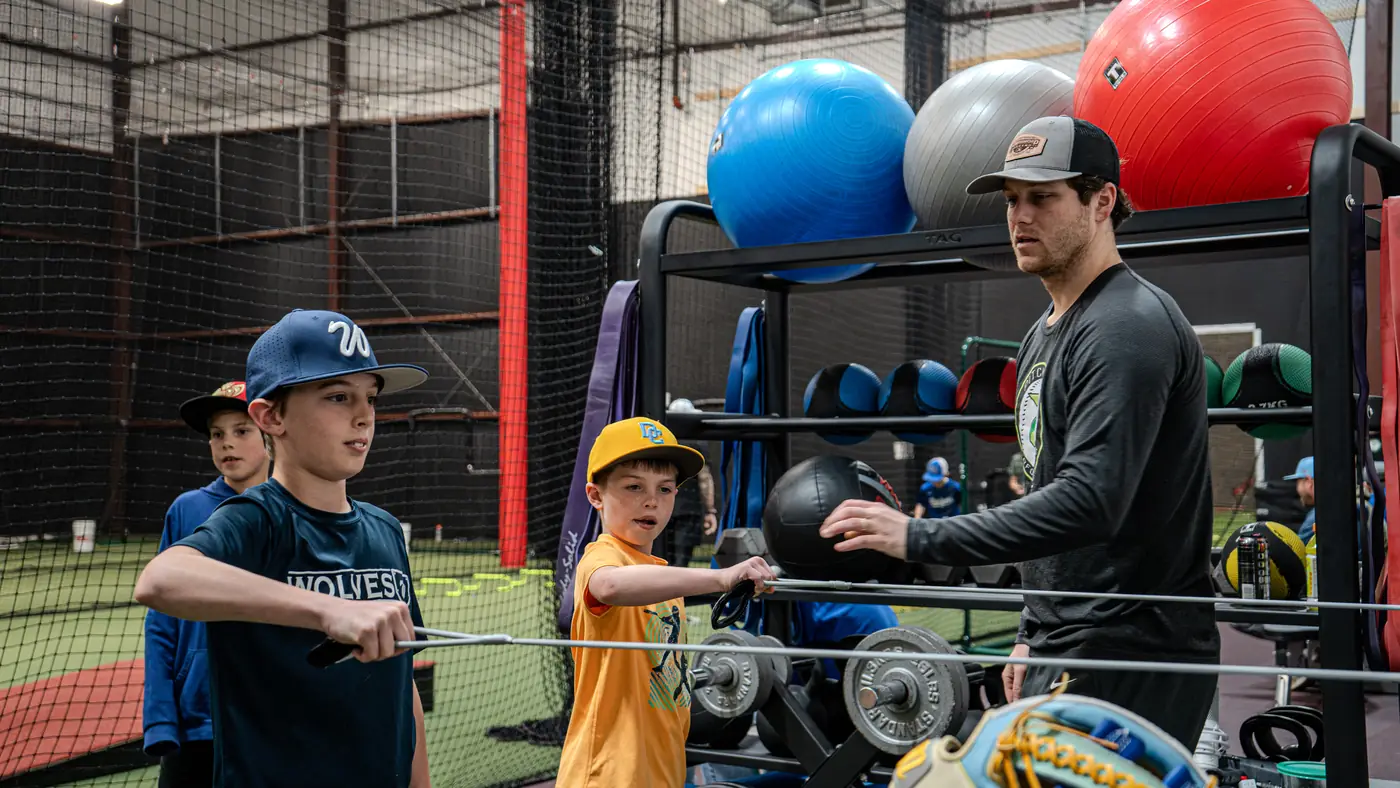 A coach working with two Academy players on a resistance bar